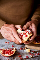 man opening a pomegranate fruit