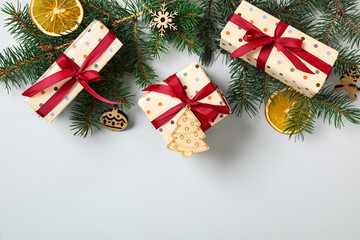 Flat lay composition with Christmas gift boxes and fir branches on grey background. Space for text