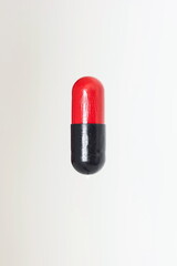 Red and black medicament capsule pill close up macro shot isolated on white