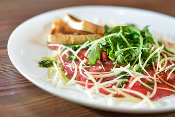 Black angus beef carpaccio with parmesan cheese on a plate