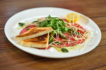 Black angus beef carpaccio with parmesan cheese on a plate
