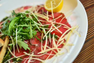 Black angus beef carpaccio with parmesan cheese on a plate