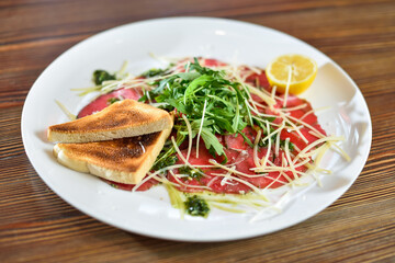 Black angus beef carpaccio with parmesan cheese on a plate