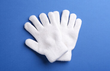 Obraz premium Pair of stylish woolen gloves on blue background, flat lay