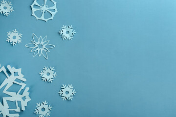 Many paper snowflakes on turquoise background, flat lay. Space for text