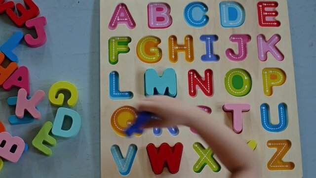Top view of a toddler boy playing alphabet puzzle to learning English 
