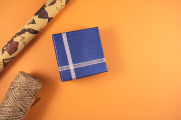 Preparation for holidays. Blue gift boxes, paper's rools and rope on orange backgruond. Preparation for holidays. Top view and copy space.