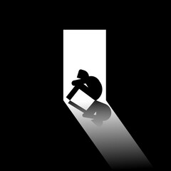 Silhouette of sad isolated person sitting alone on the floor huddled in doorway mental health concept.