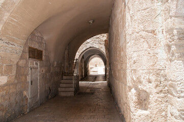 Walking down the street through a stone arch with a flat stone pavement