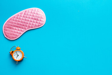 Sleep disorder stress concept. Sleeping mask with alarm clock, flat lat,top view