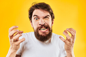 emotional bearded man gesturing with hands aggression discontent close-up yellow background