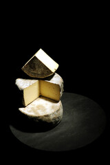italian cheese called Toma from Piemonte region whit cutting light on black backdrop