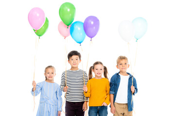 Smiling multiethnic children holding balloons isolated on white