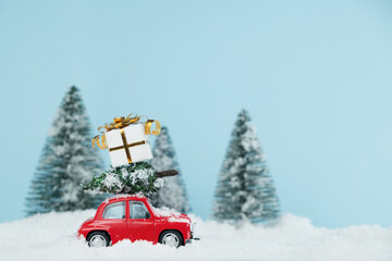 Christmas red car with a gift box in a snowy pine forest. Space for text. Happy New Year card concept