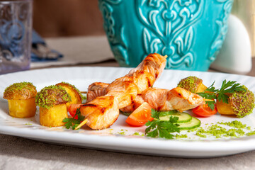 Grilled salmon kebab served with tomatoes cucumbers and baked potatoes with spices