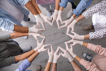 People in white medical gloves showing hearts with fingers indoors, top view