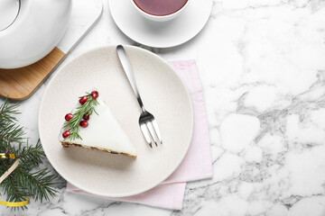 Slice of traditional Christmas cake decorated with rosemary and pomegranate seeds served on white marble table, flat lay. Space for text