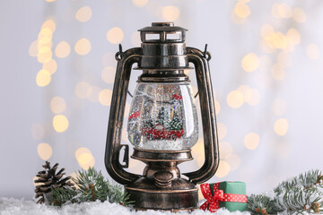 Snow globe in vintage lantern and Christmas decor against blurred festive lights