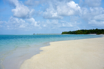 Golden beach under blue sky and clear blue water in the maldives