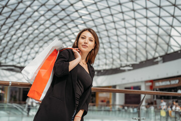 Fototapeta premium Beatiful dark-haired girl with a shopping bag at the mall