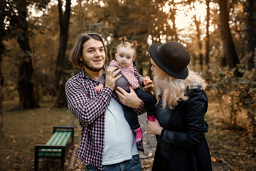  Father, mother and a 6 month old baby girl are posing in a fall park. Happy family concept