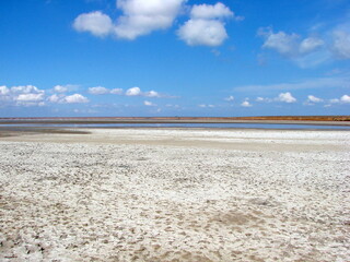 Landscape of blue barely cloudy sky reflected on the water surface of a semi-dried salt lake.