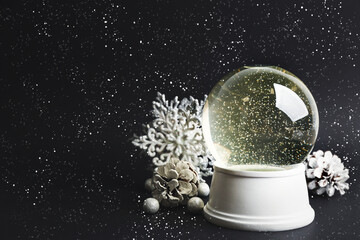 Beautiful snow globe and Christmas decorations on dark grey background. Space for text