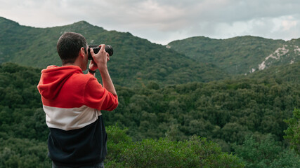 Back half body view of a photographer taking pictures on the mountains of Sardinia