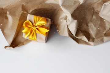 Single gift box wrapped by kraft brown paper with beautiful yellow satin ribbon. Snow falling effect. Universal gift design for all kind of celebration.