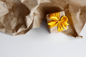 Single gift box wrapped by kraft brown paper with beautiful yellow satin ribbon. Universal gift design for all kind of celebration.