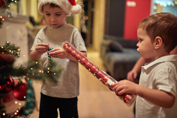 Children playing while decorating a Christmas tree at home together. Together, New Year, family, celebration