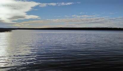 Flood of the Vuoksa river under the blue sky.
Leningrad region. Summer day. Vuoksa river. The calm waters of the river flow under the clouds against the bright sky. Light ripples on the water. a dark 