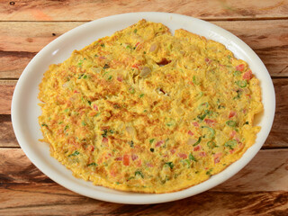 Indian Masala Egg Omelet, made with fresh vegetables tomato,onion, hot chili pepper, parsley.. served in rustic wooden background, selective focus