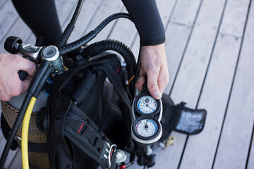 Scuba diver kitting up and checking the pressure gauge, close up of hand holding equipment.