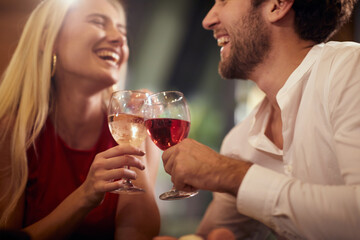 A young couple in love toasting and laughing at Valentine's day celebration at a restaurant. Together, Valentine's day, celebration