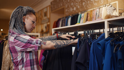 Young woman choosing clothes on rack in modern vintage store