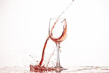 splash and flow of red wine in a glass on a white background with reflection