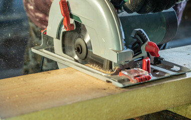Worker carpenter is sawing a wooden Board with a hand-held circular saw