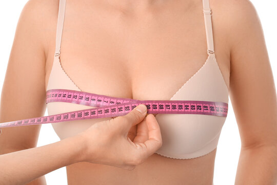Measuring of young woman's breast against white background