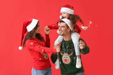 Happy family with Christmas sparklers on color background
