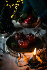 Christmas baked apples stuffed with nuts, lingonberry and cinnamon on  big green plate on festive decorated table..