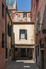 Fototapeta na wymiar street view of narrow alley with unique architecture of residential building bridge underpass in venice italy