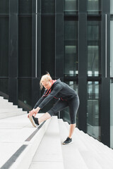 Junge, attraktive Frau dehnt sich auf einer Treppe