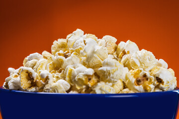 cooked popcorn in a plate on a orange background