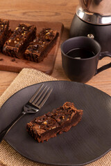 plate with a slice of brownie and a few slices in the background and a cup of coffee