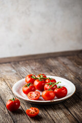 Fresh tomatoes in a plate with basil leaves preparing for the preservation on old wooden table. Organic food.