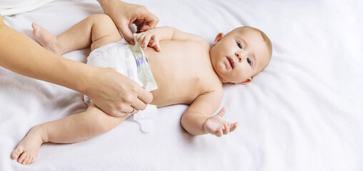 The mother changes the baby's diaper. Selective focus.