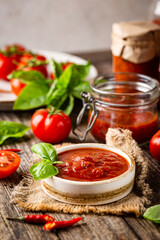 Bowl of italian tomato sauce with basil and fresh tomatoes on wooden background
