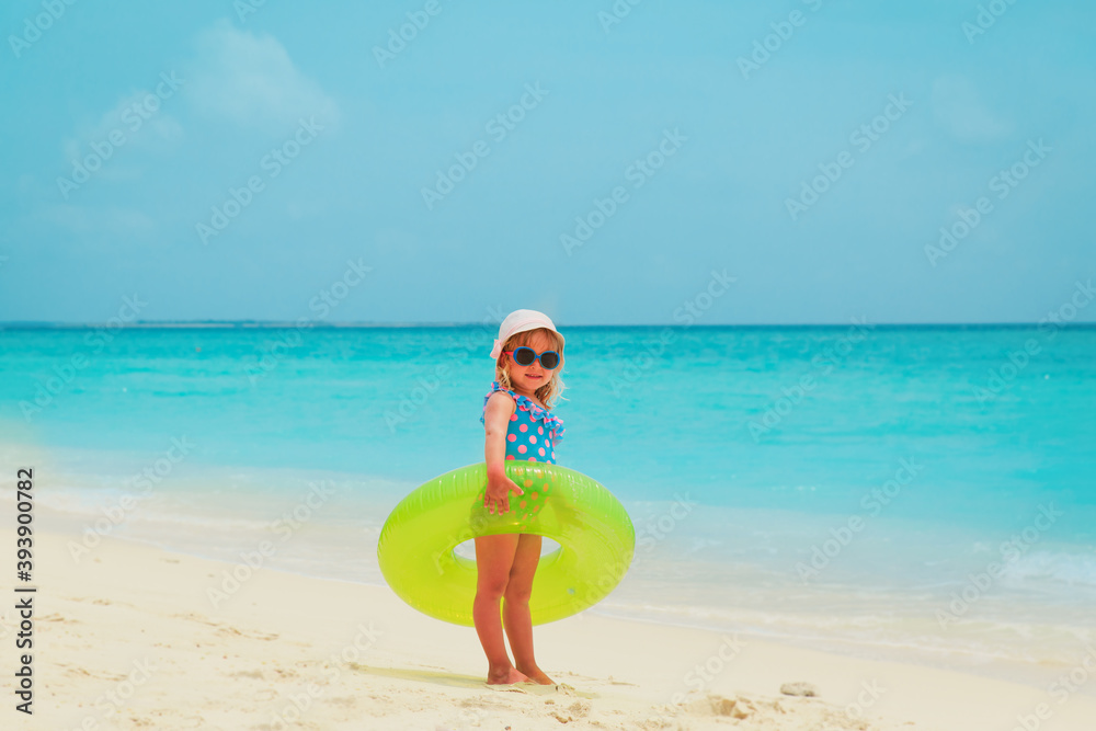 Wall mural happy cute little girl with floatie at tropical beach