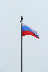 Russian flag on a light sky background, white, blue and red tricolor